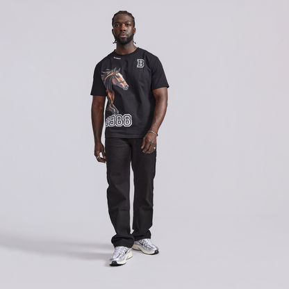 Man wearing a black t-shirt with a horse graphic and text, standing against a plain background