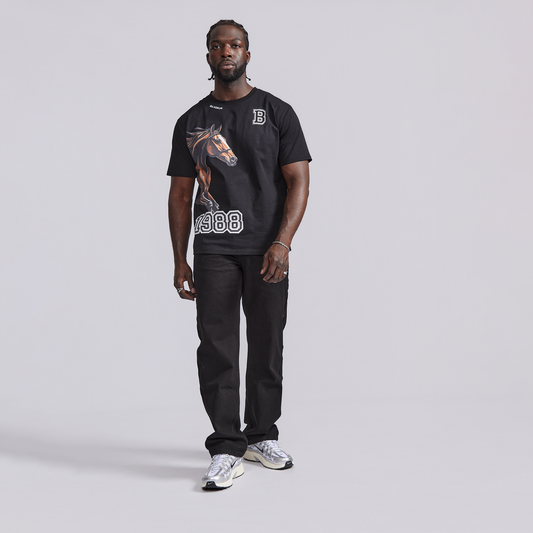 Man wearing a black t-shirt with a horse graphic and text, standing against a plain background