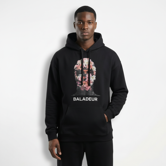 Person wearing a black hoodie with floral design and 'BALADEUR' text on a white background