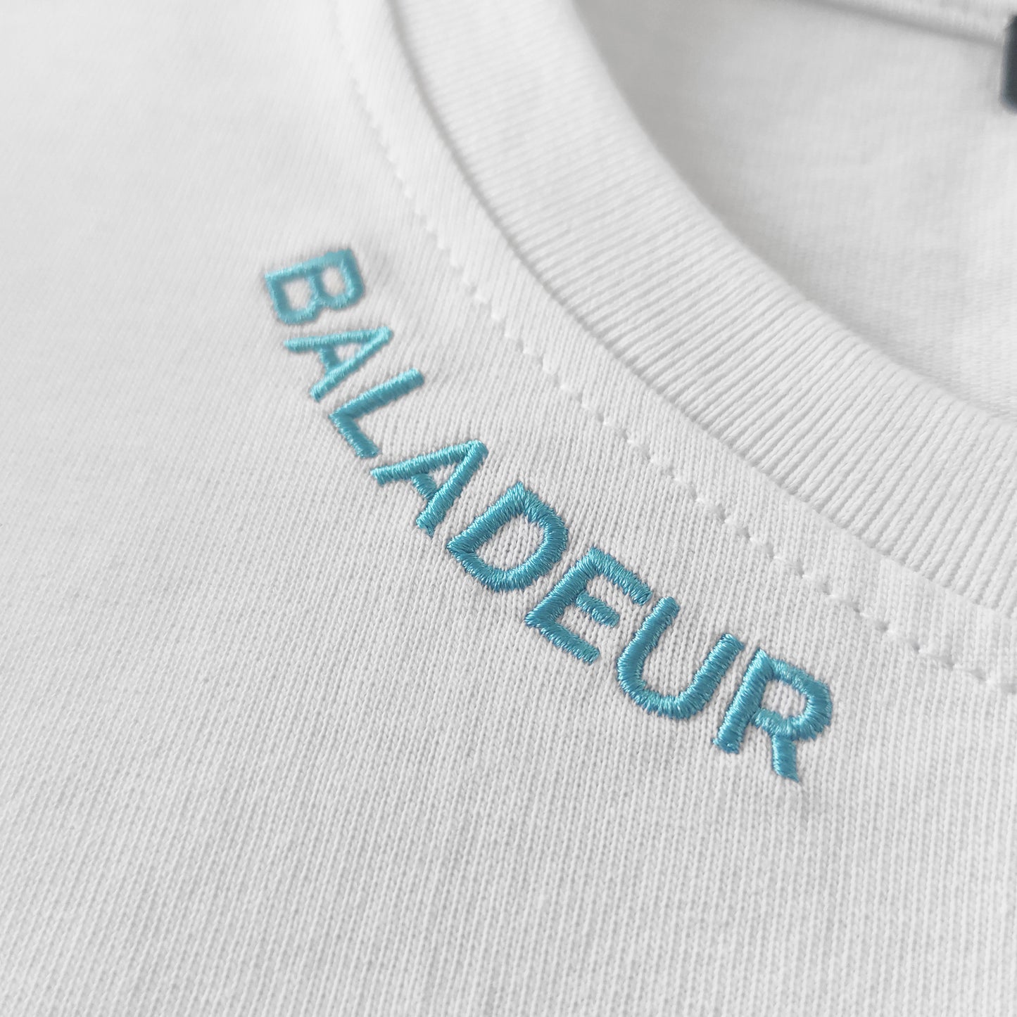 White sweater with 'BALADEUR' embroidered in blue on a white background